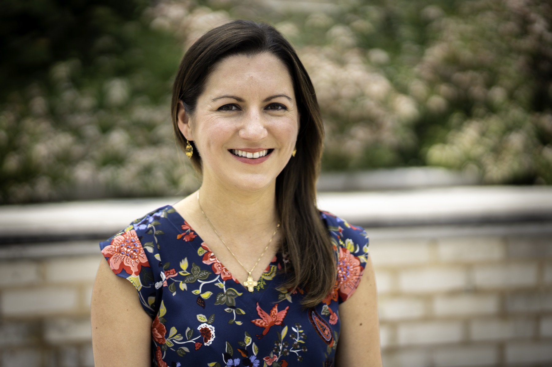 Outdoor headshot with flowering greenery in the background